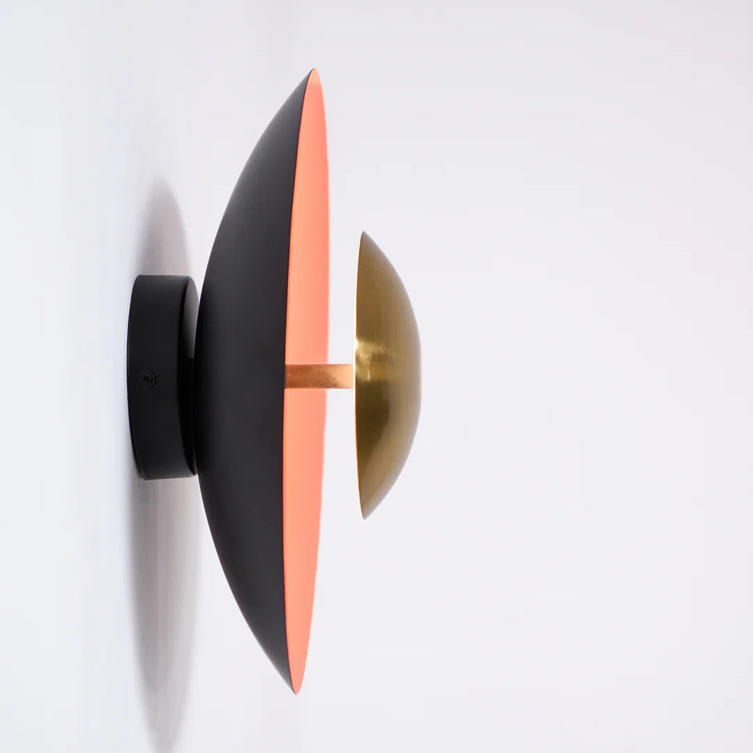 Modern wall light fixture with black, orange, and gold design on a white background
