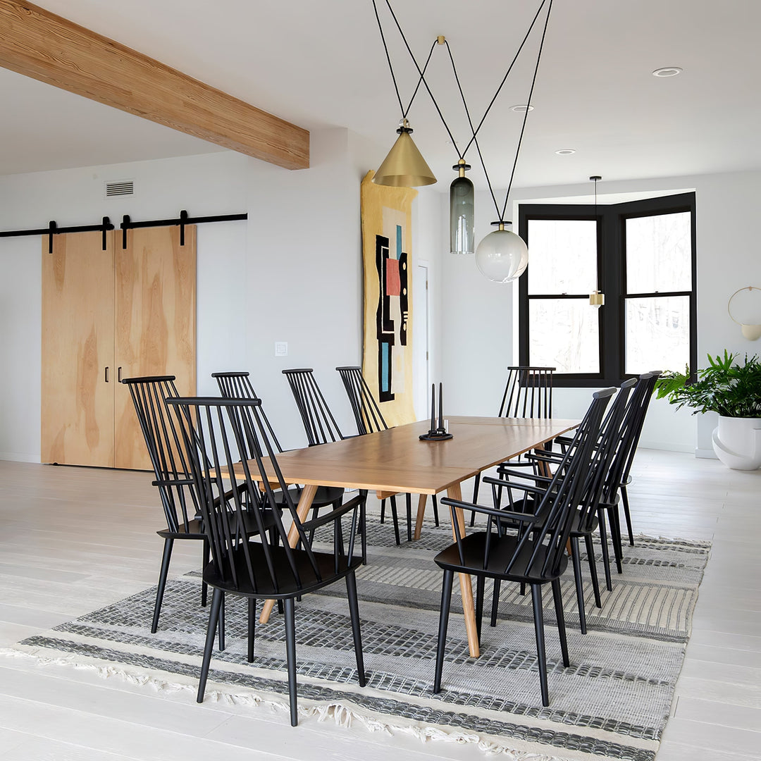 Modern dining room with wooden table and black chairs on a gray rug.