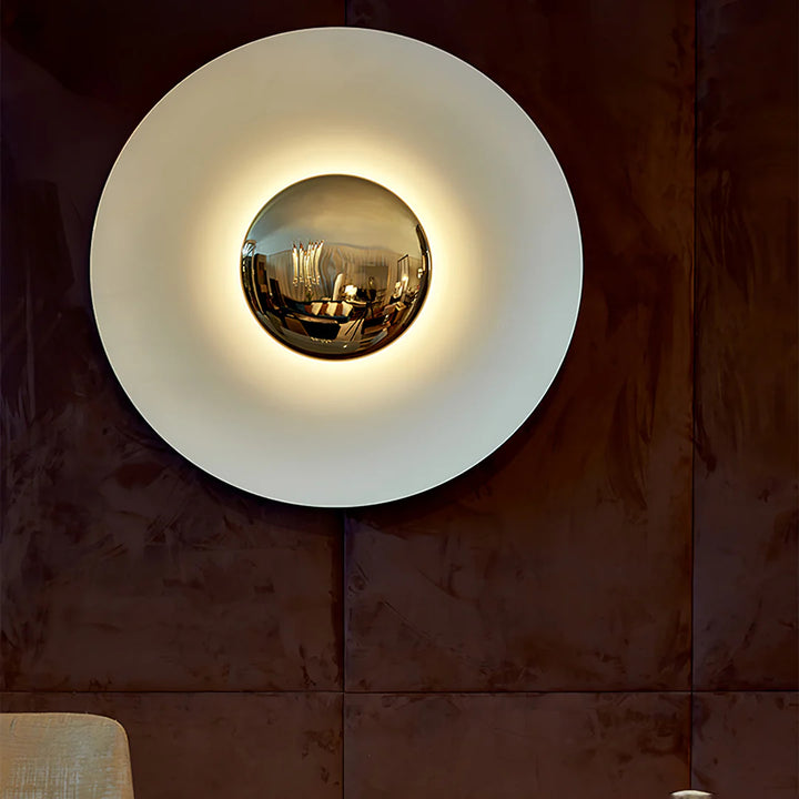 Round wall light fixture with reflective surface on a textured wall.
